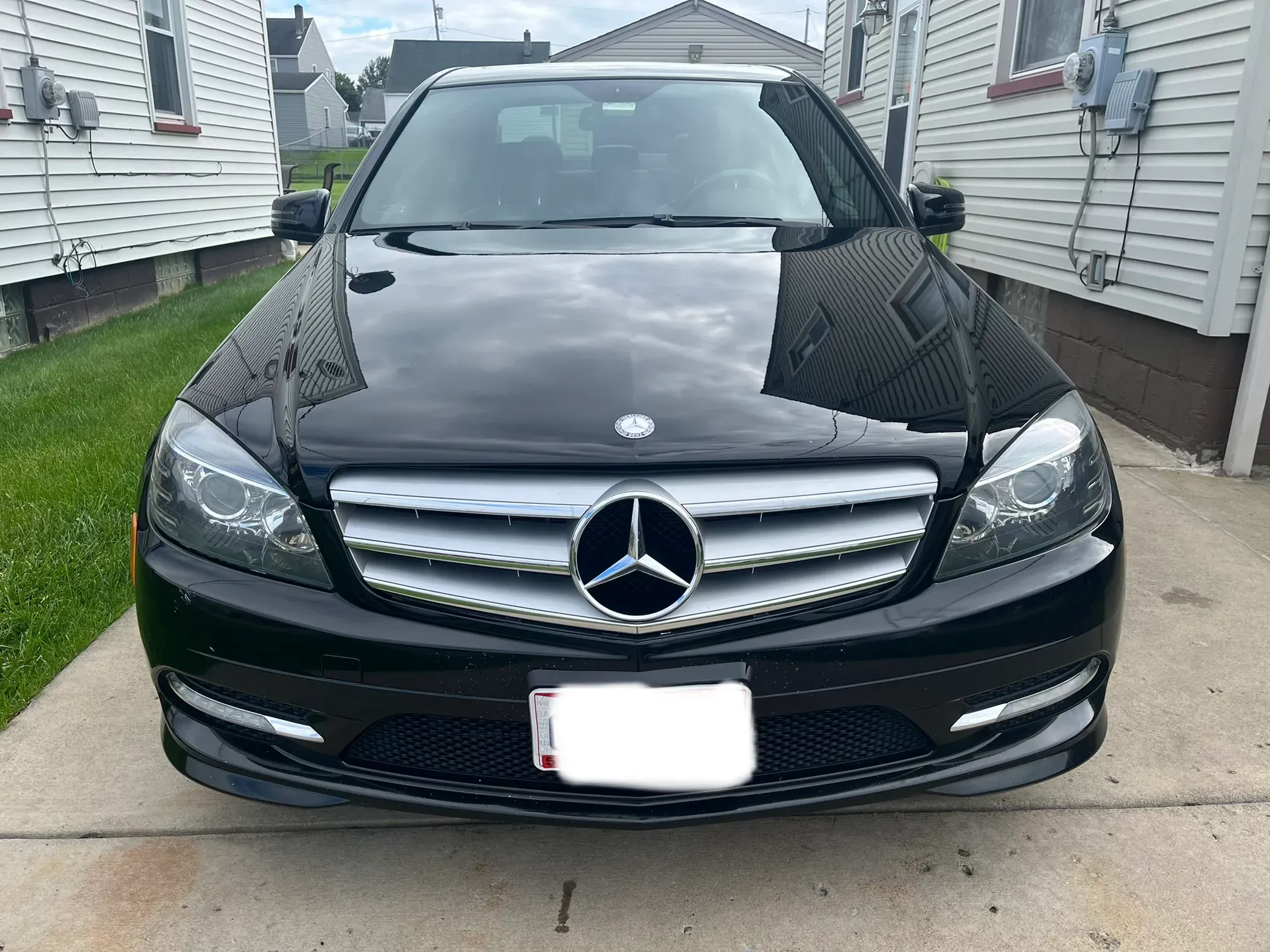Polished hood and grille of a black Mercedes-Benz sedan.