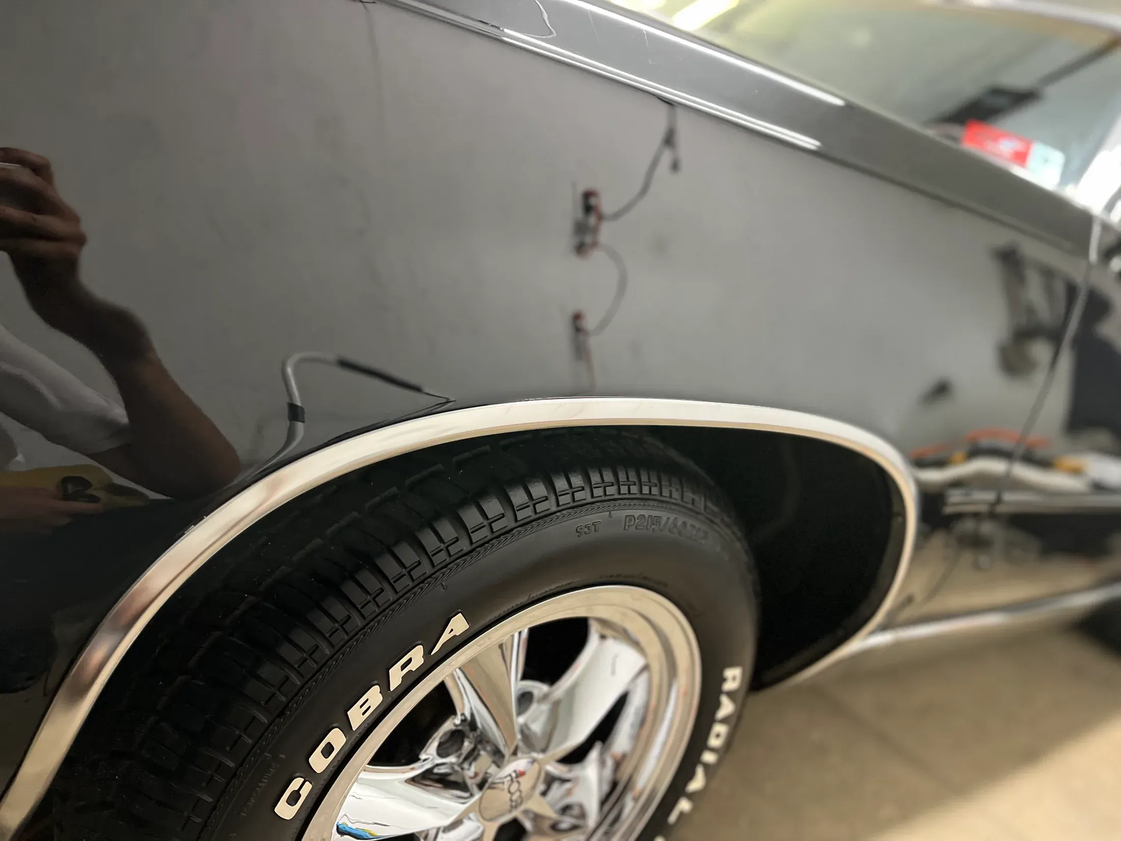 Polished front fender and white-letter tire on a classic black car.