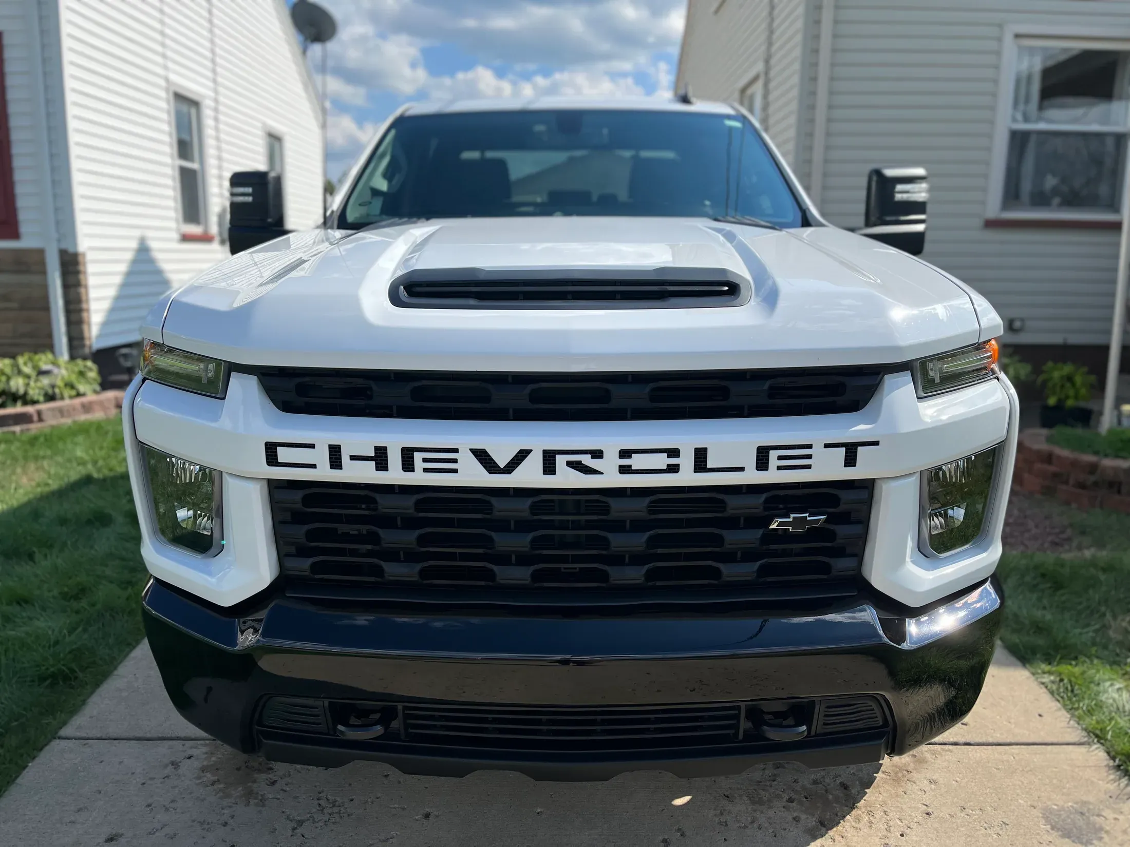 White Chevrolet Silverado HD beside a touring motorcycle.